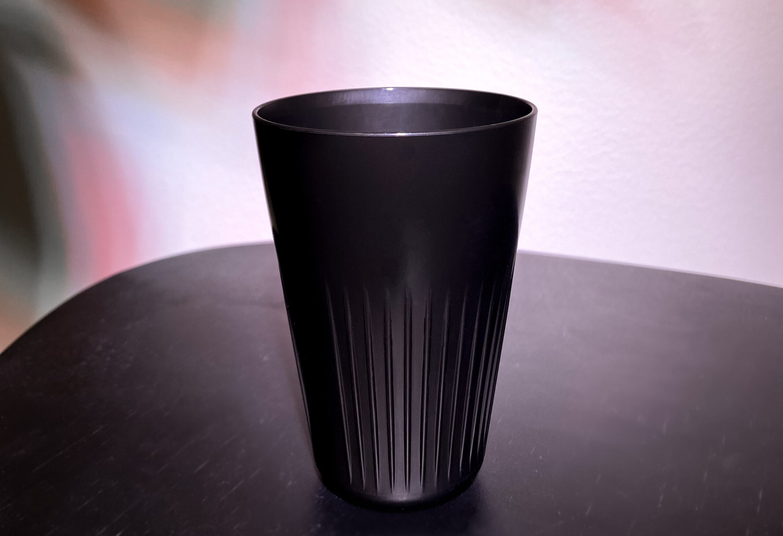Black mug on a black wooden table with some foggy leaf shadows in the background